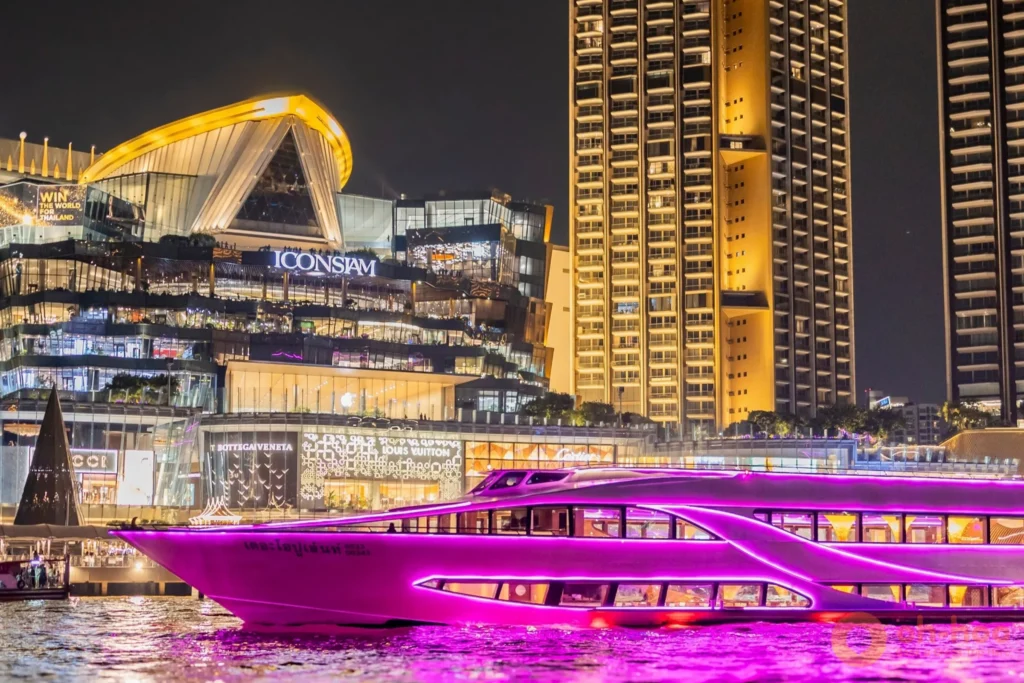 The Opulence luxury dinner cruise vessel illuminated at night sailing past ICONSIAM on the Chao Phraya River